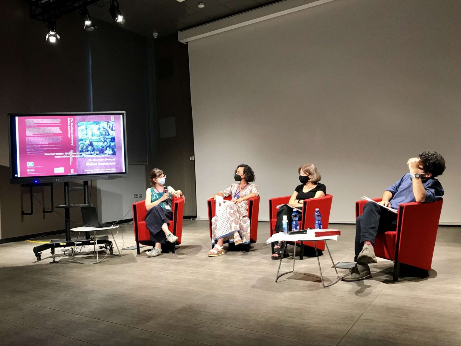 Panelists sit on chairs on stage at Teresa Fiore book presentation at University of Turin