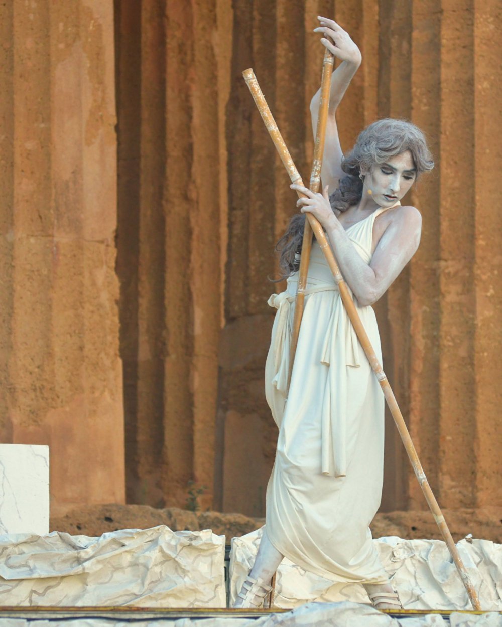 A woman in an ancient Greek costume poses on stage