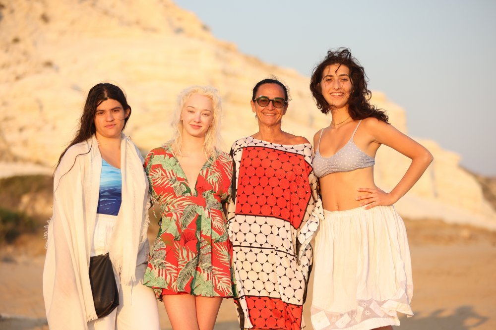 A group of four people post outside in front of a large rock formation
