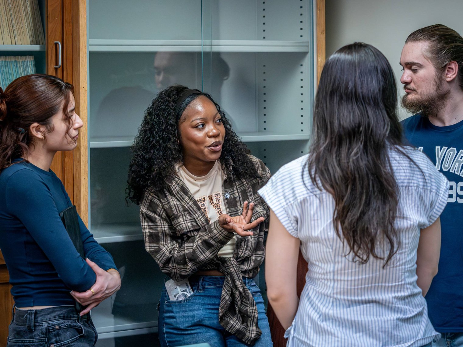 A group of college students talk together in a classroom