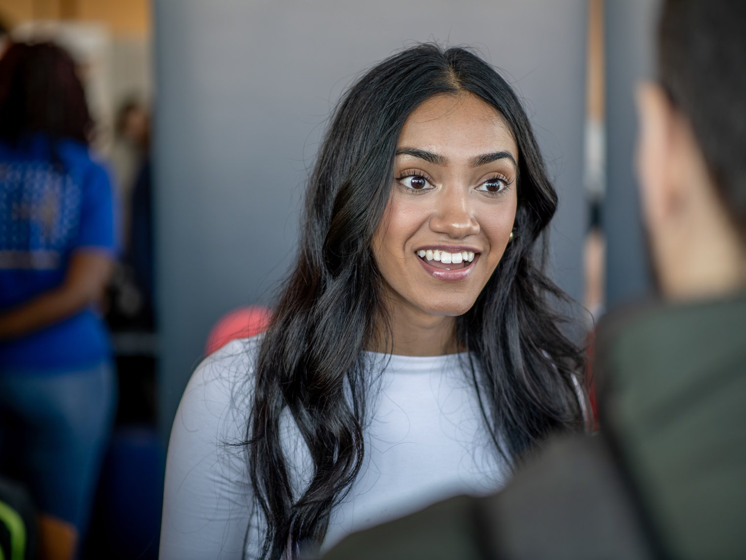 Student smiles while speaking with a representative at a career fair.