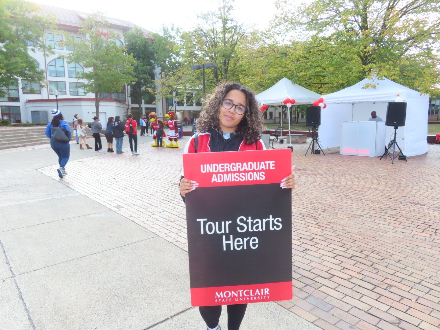 Tahina holds a “Your Story Starts Here” sign at a campus tour.