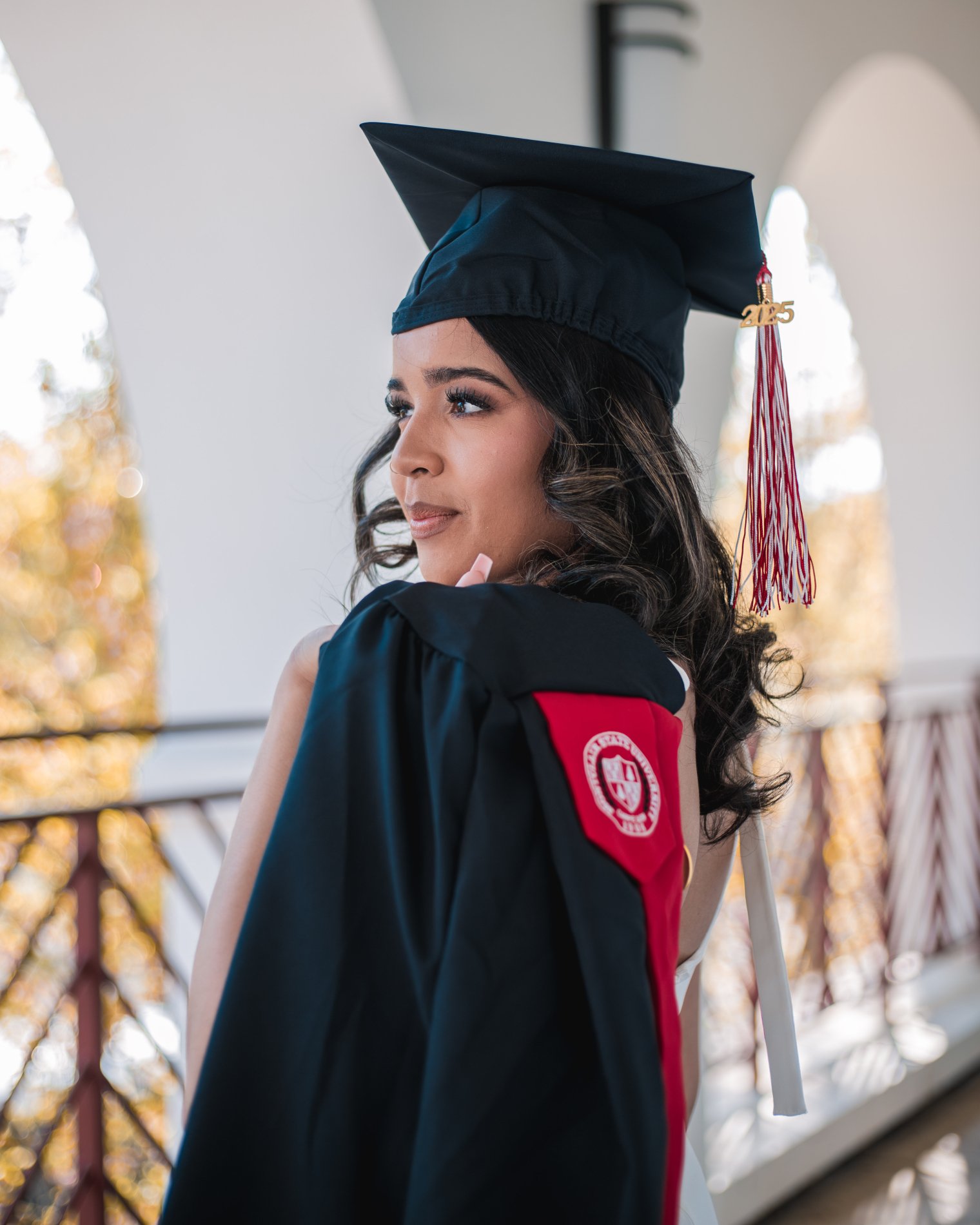 Tahina smiles in a her cap and gown outdoors on campus.