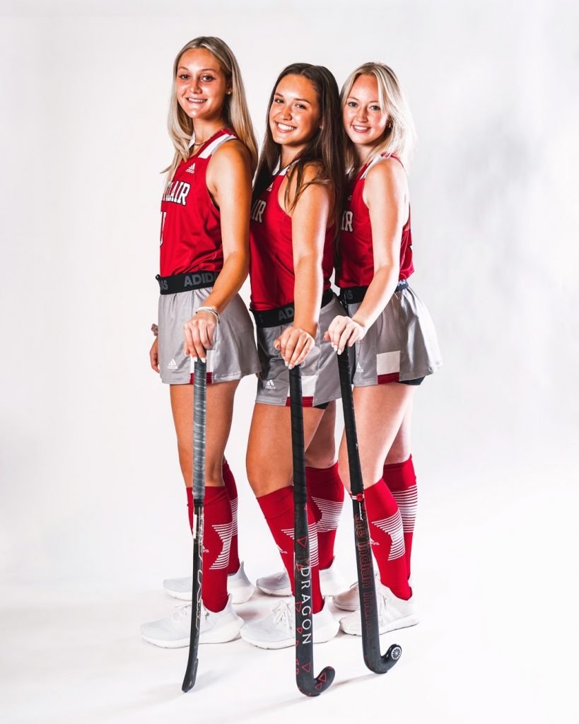Three college athletes pose for a photo in their jerseys.