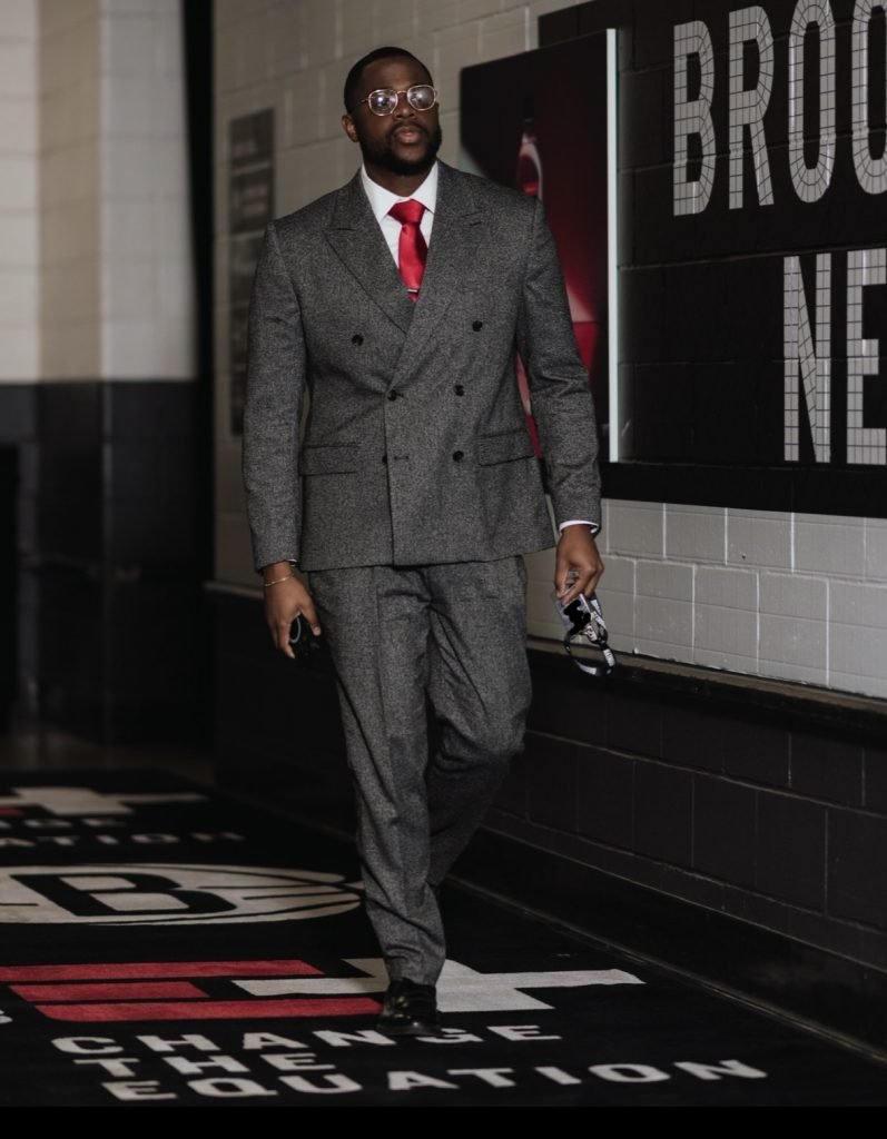 Jon walking down a hallway in a gray suit.