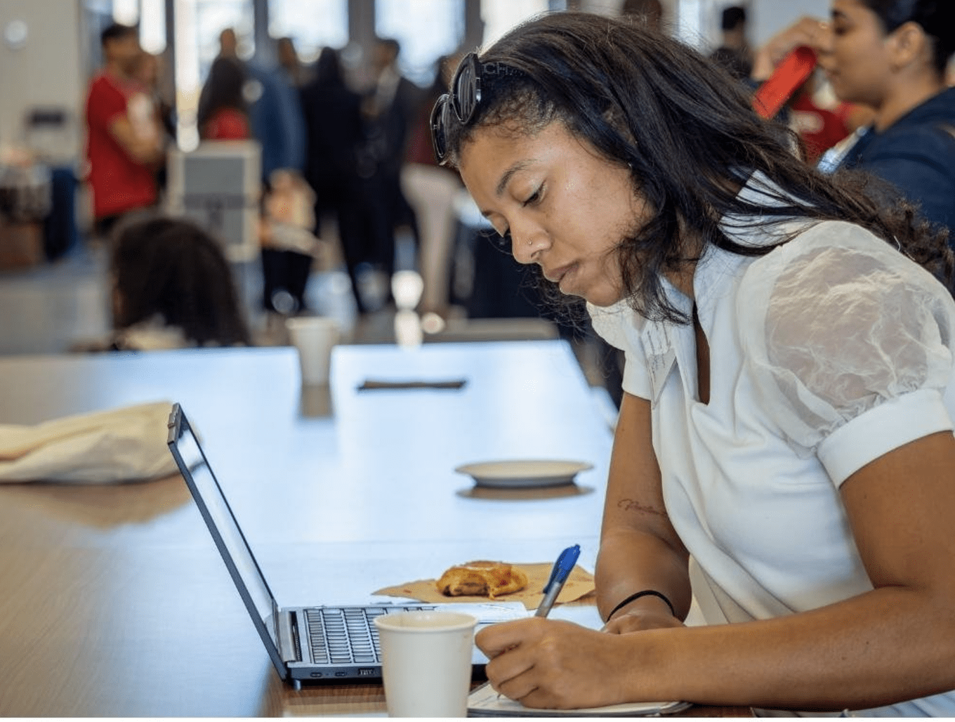 woman sitting with her laptop and coffee writing something down