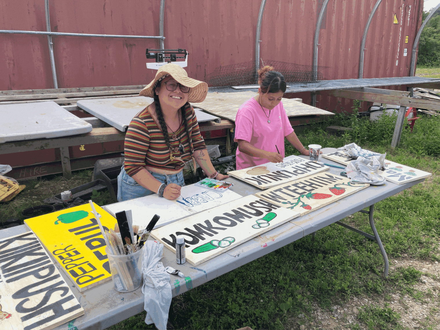 A woman paints a sign at a table