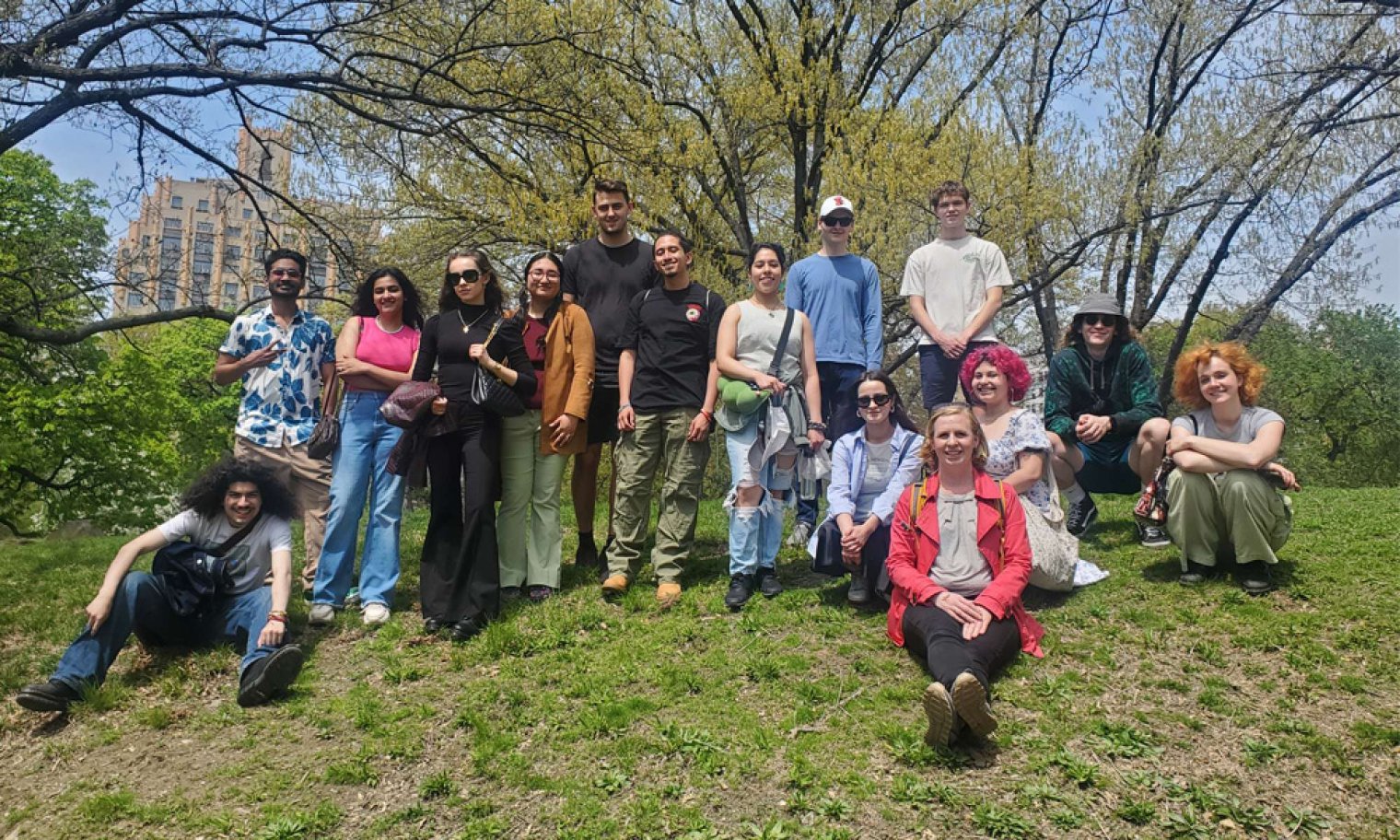 A group of college students and a professor pose togehter in a park