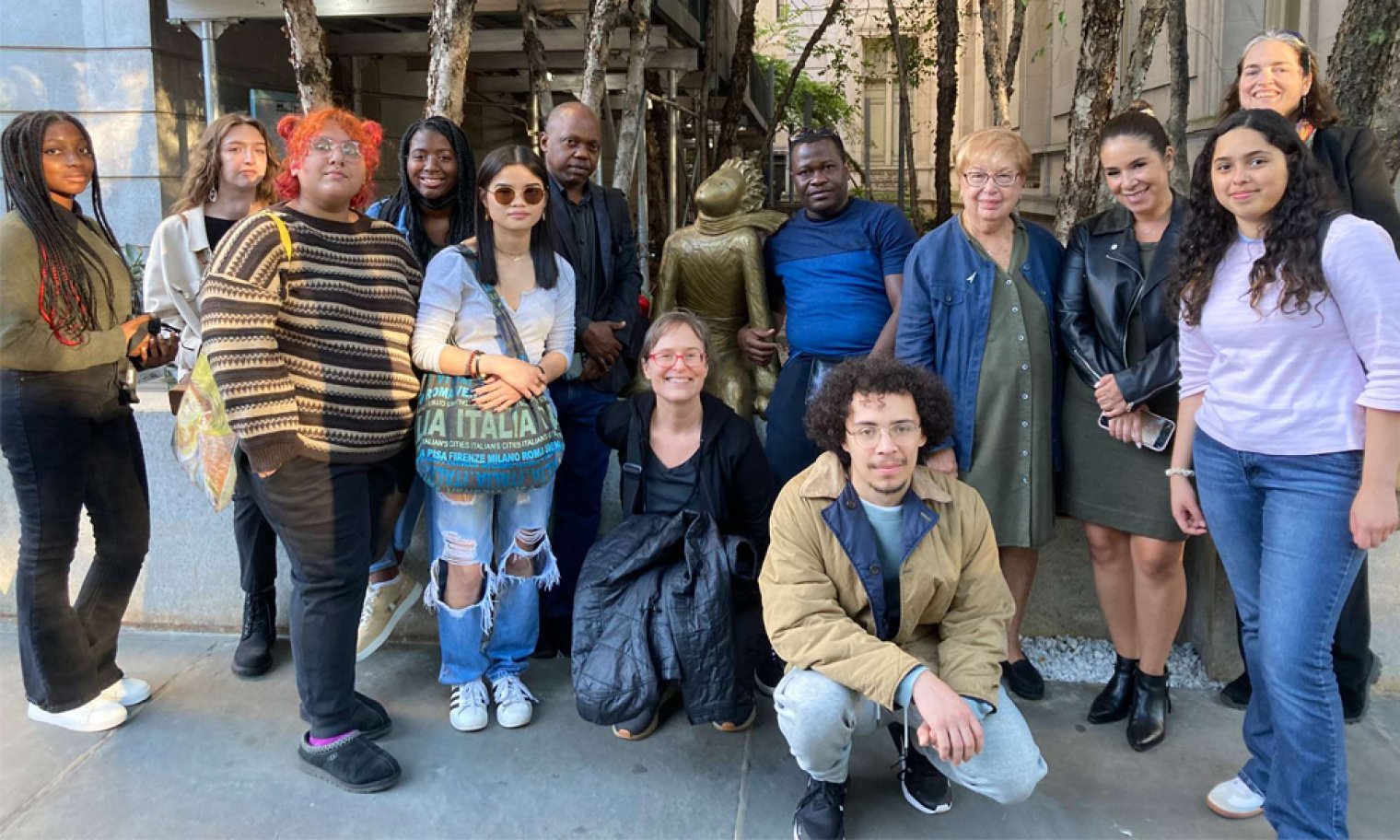 A group of college students pose with a bronze statue of the Petit Prince in New York City