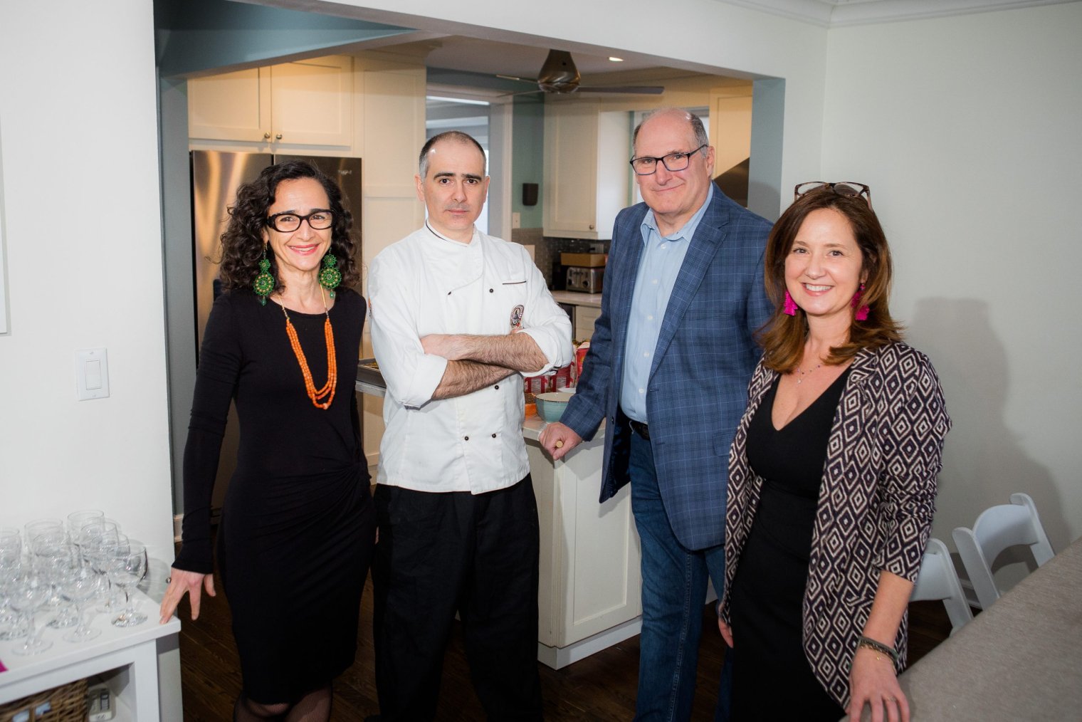 Four people standing in front of a kitchen and posing