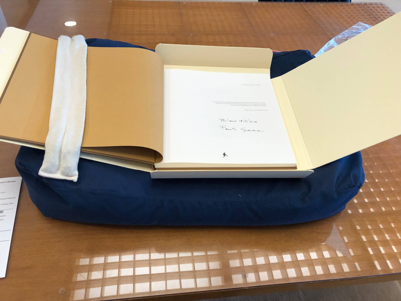 A hardbound book is open to the top page and is carefully presented on a page