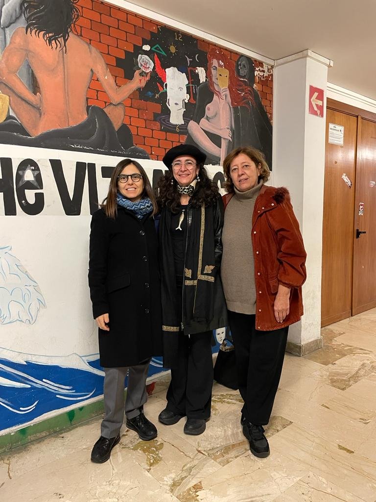 A group of three people pose in front of a mural in a hallway