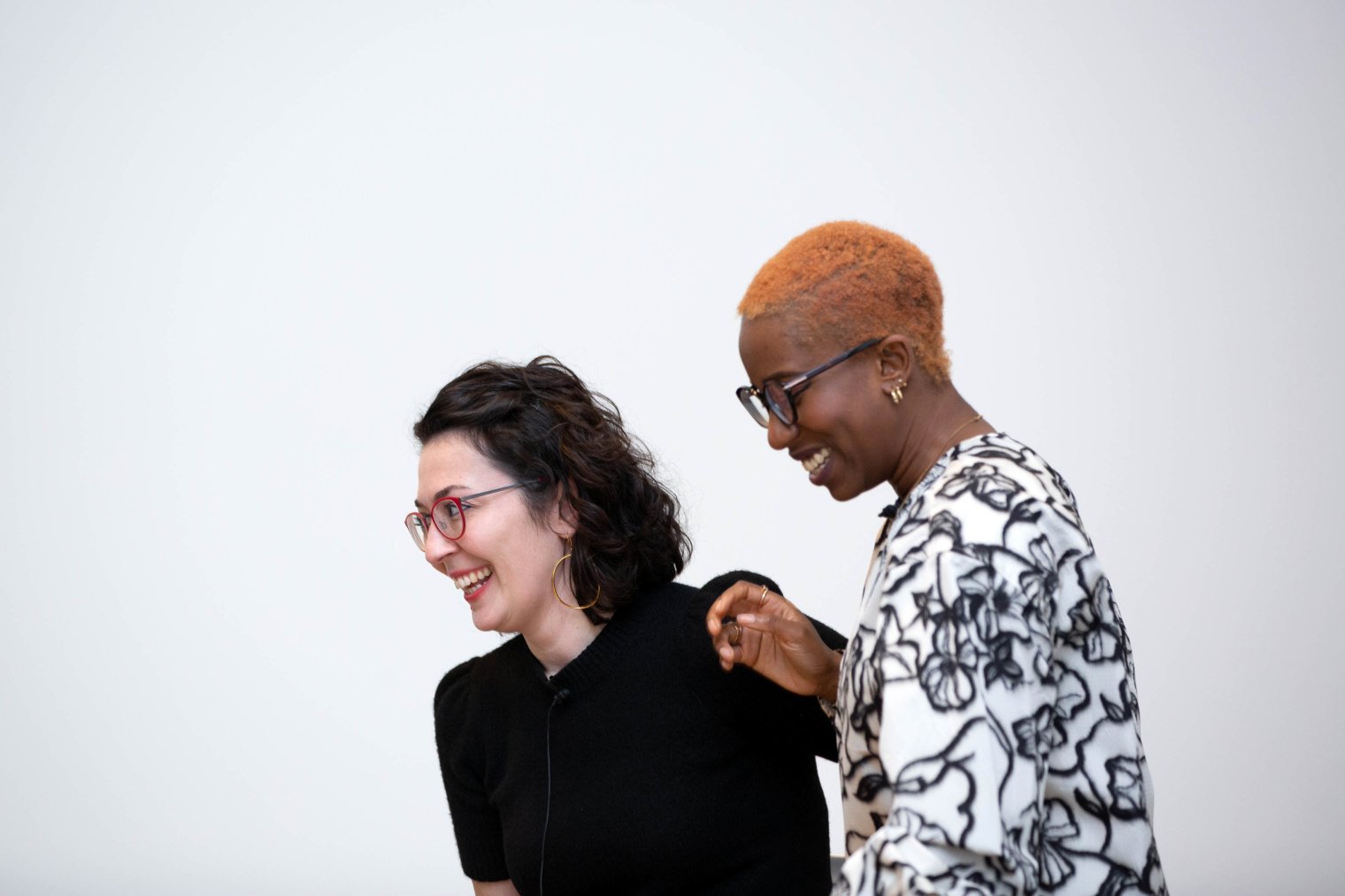 Two people stand beside eachother and laugh