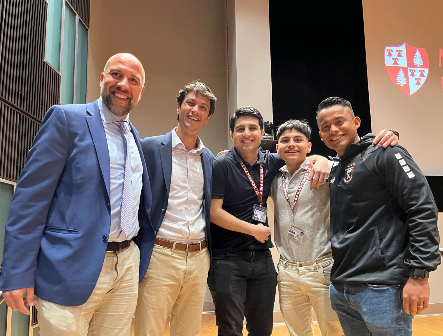 A group of five people post in front of a projector screen
