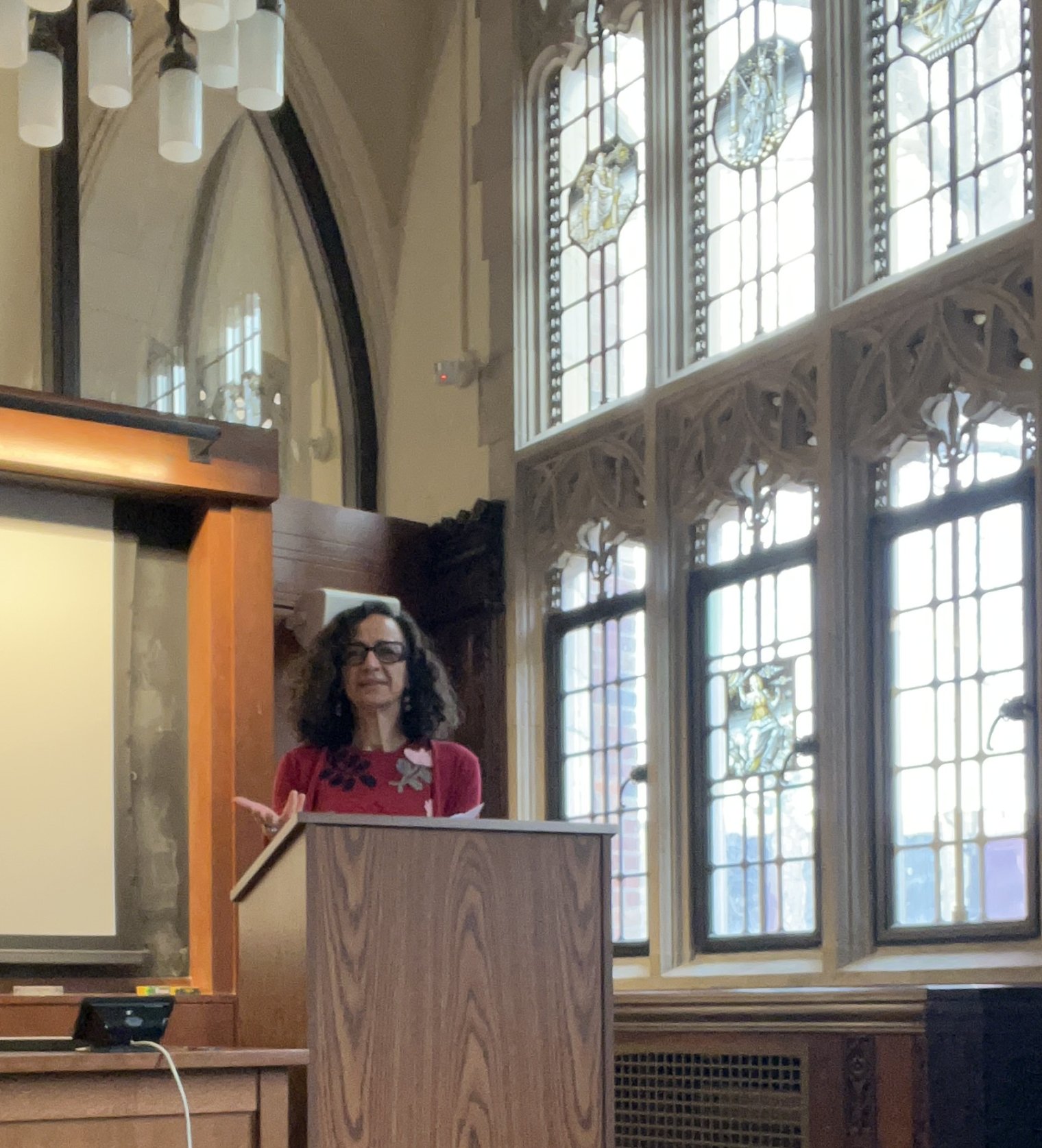 A woman stands at a podium in a church and delivers a lecture