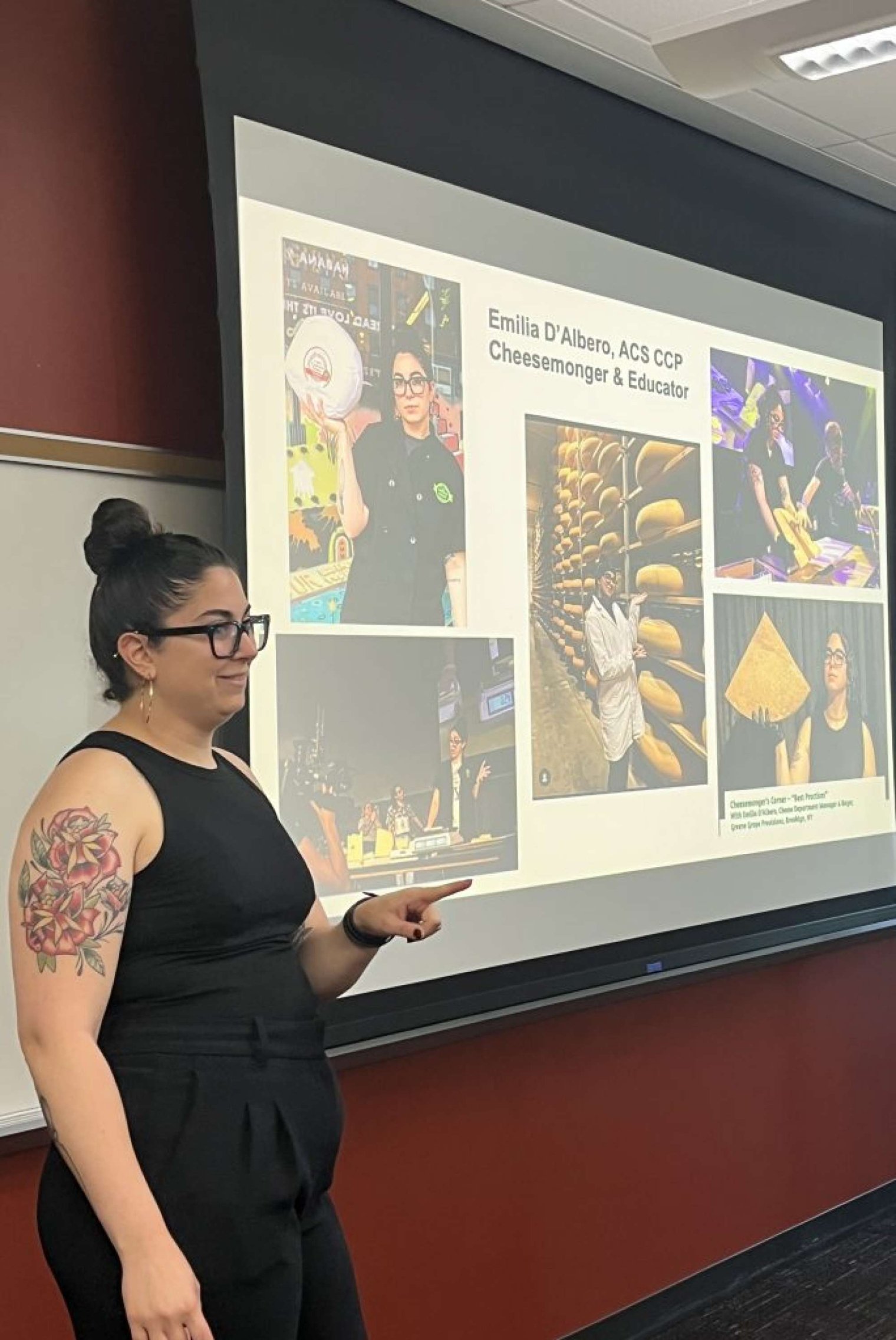 A woman stands at a projector screen and points to the audience