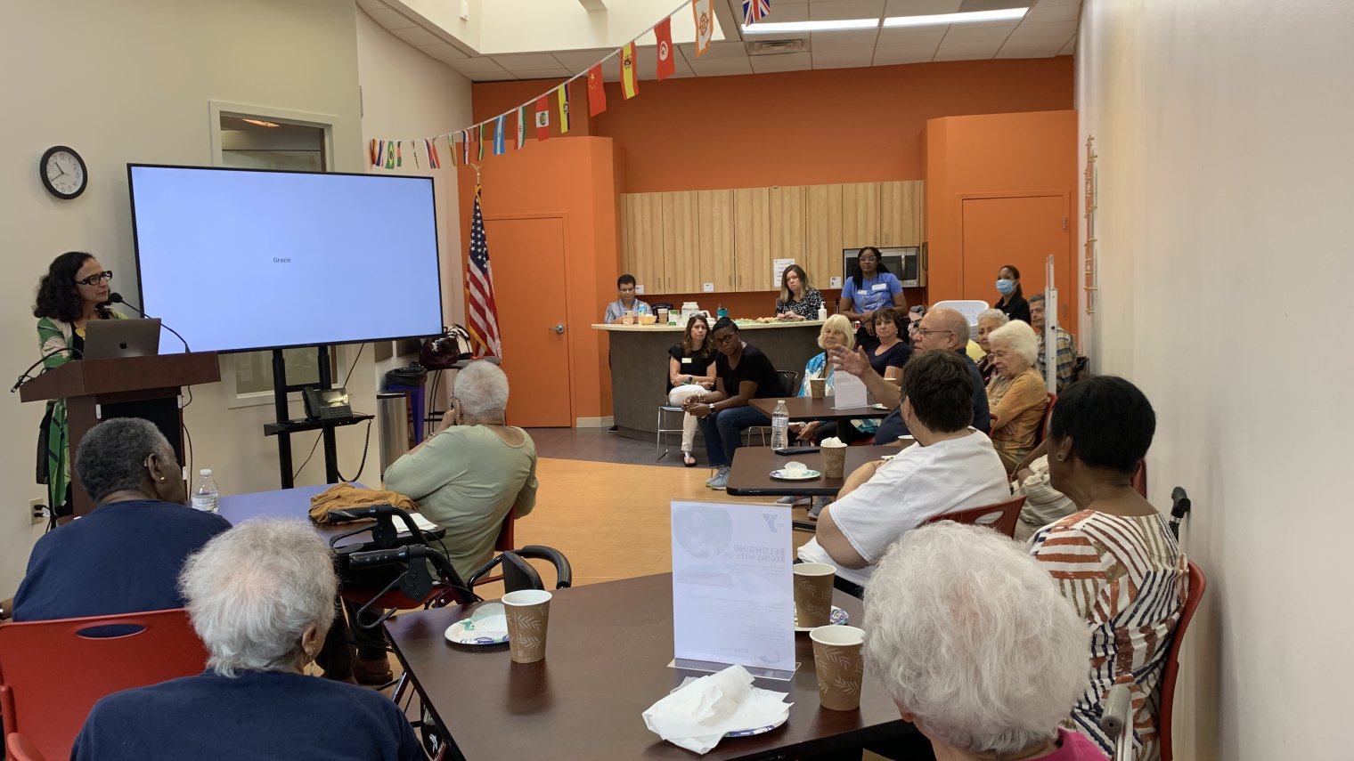 A woman delivers a presentation to a group of elderly people