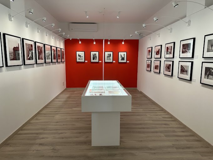 The interior of an art museum with frames on the wall and glass displaytable in the middle