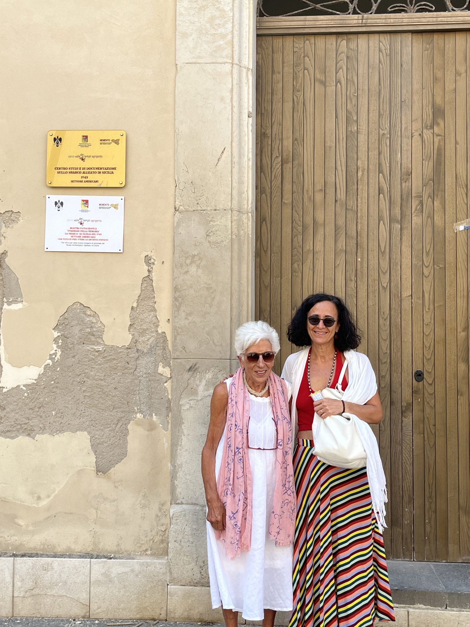 Two women pose outside a door on an Italian street