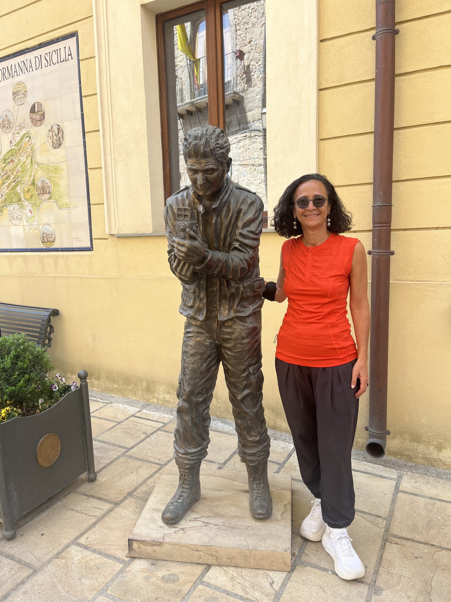 A woman stands with a metal sculpture outdoors in Italy