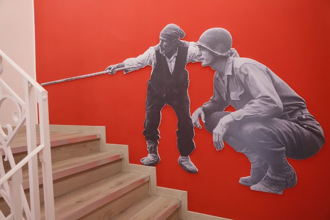 A wall cut-out depciting a U.S. WW2 soldier receiving guidance from an older man