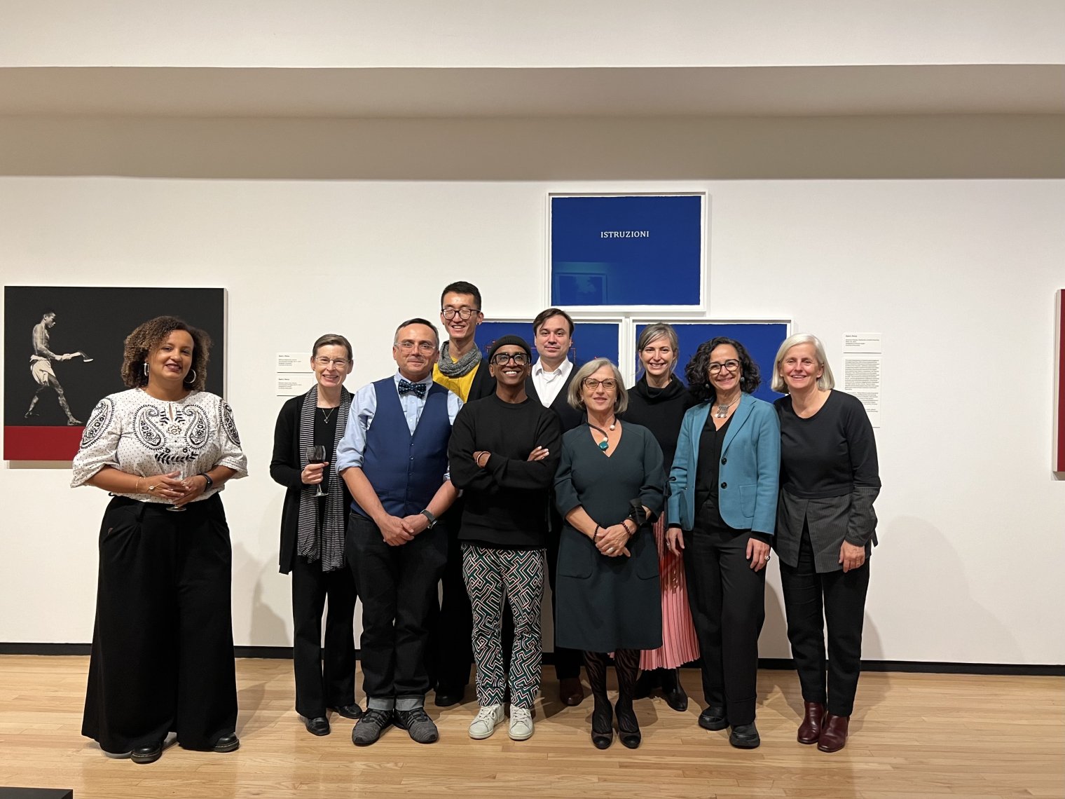 A large group of people pose in front an art piece inside a gallery