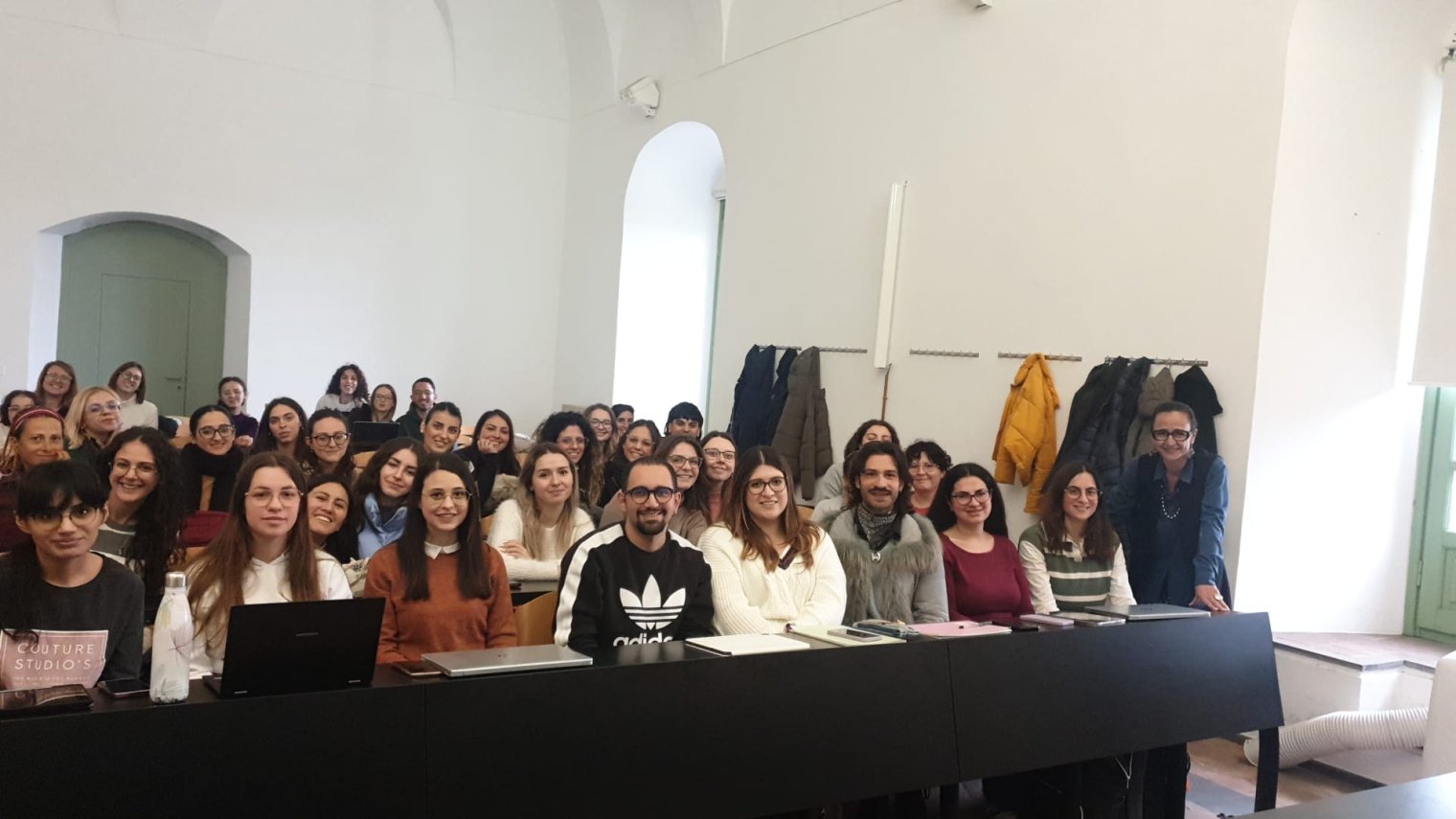 A crowded classroom of college students posing with the professor