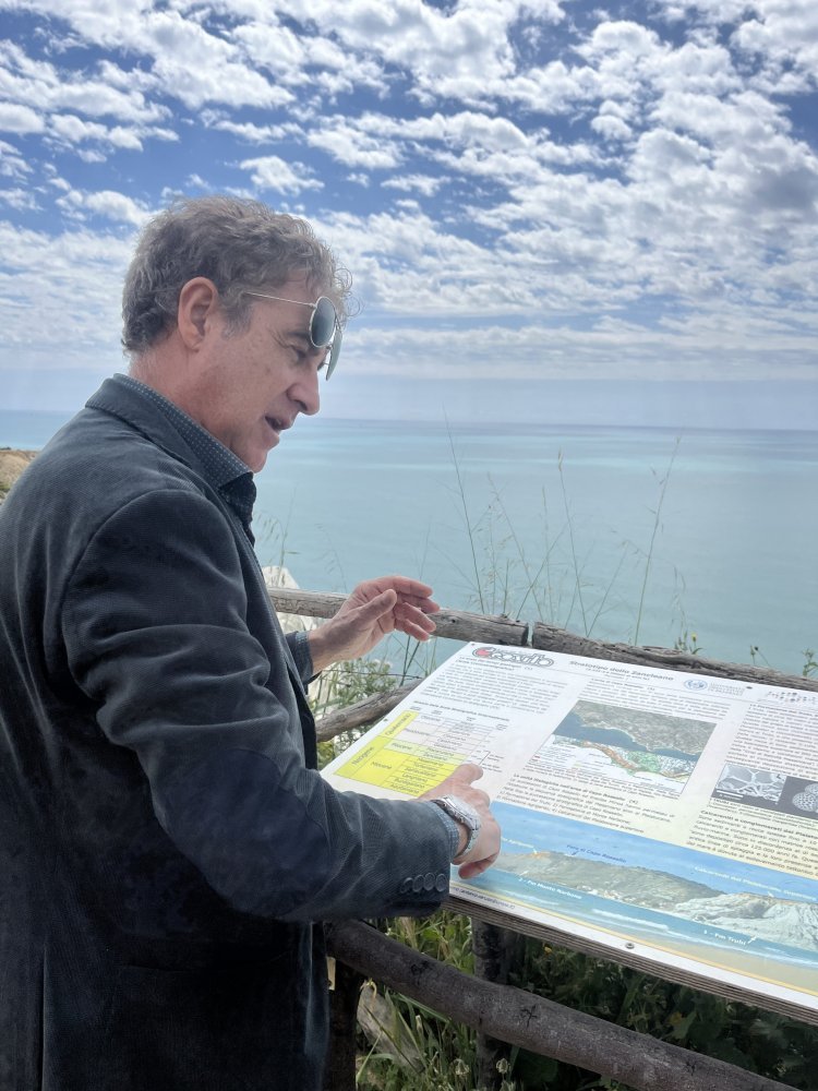 A man reads an information display by the ocean