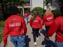 Students wearing their content creator program jackets walking through campus. 