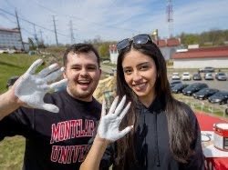 Two students with their hands in white paint.