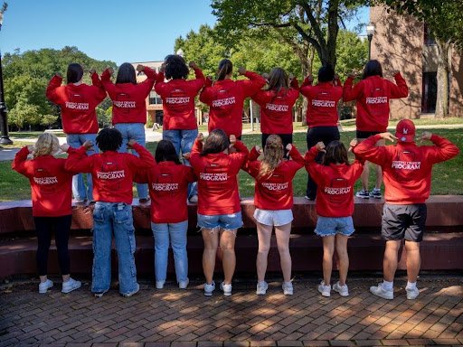 Students part of the Content Creator Program are turned around, wearing red sweaters pointing to the text "Content Creator Program."