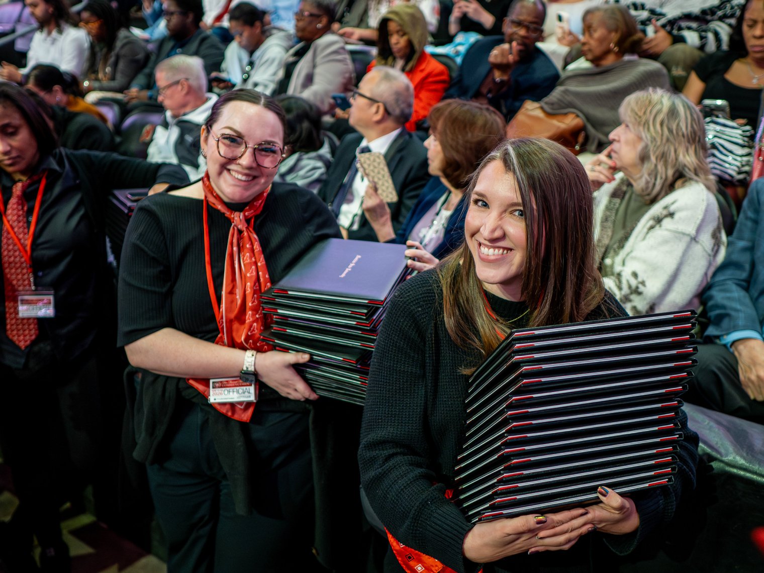 Staff working Commencement hold stacks of diploma covers