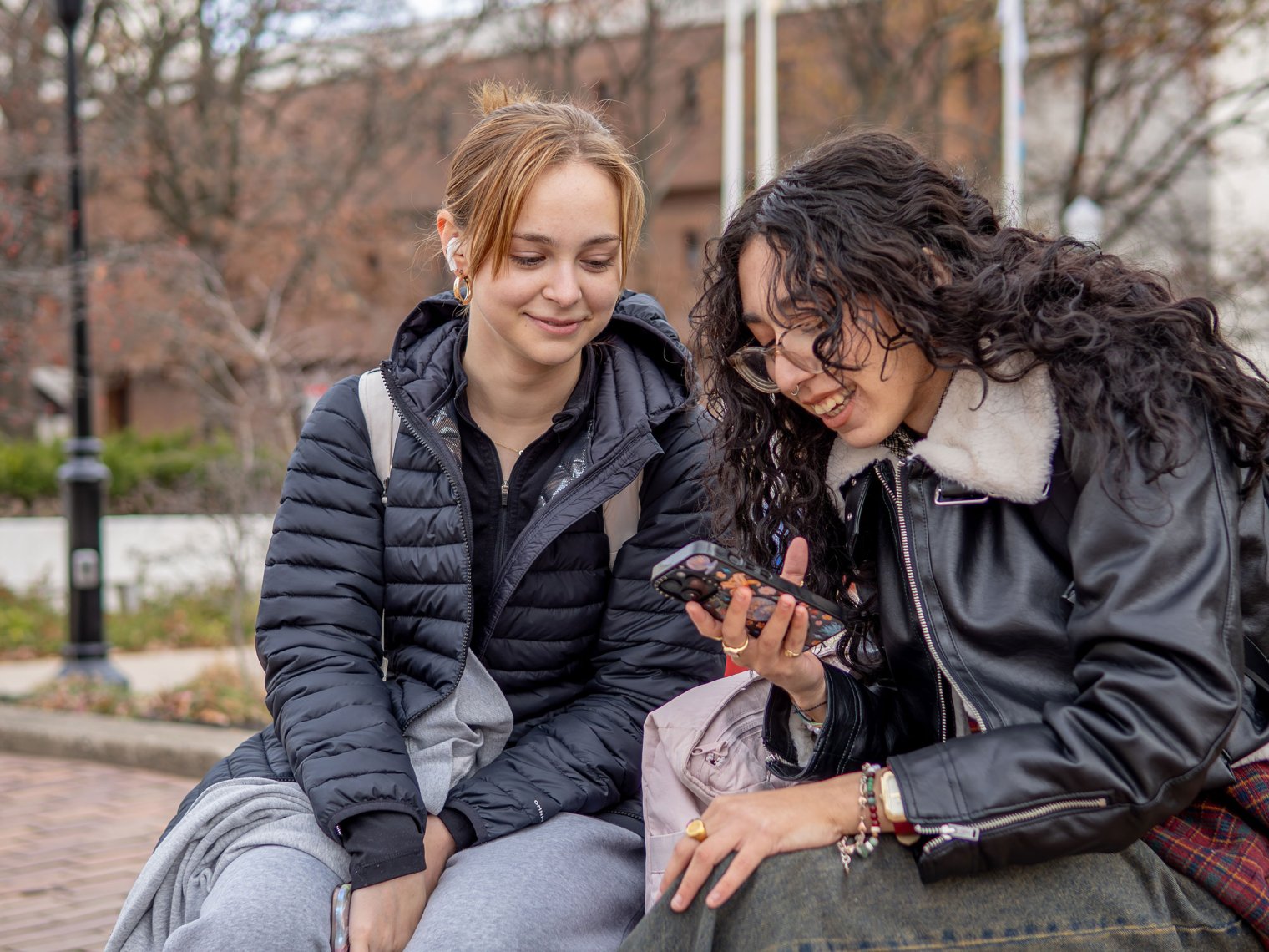 Two students looking at a phone and smiling.