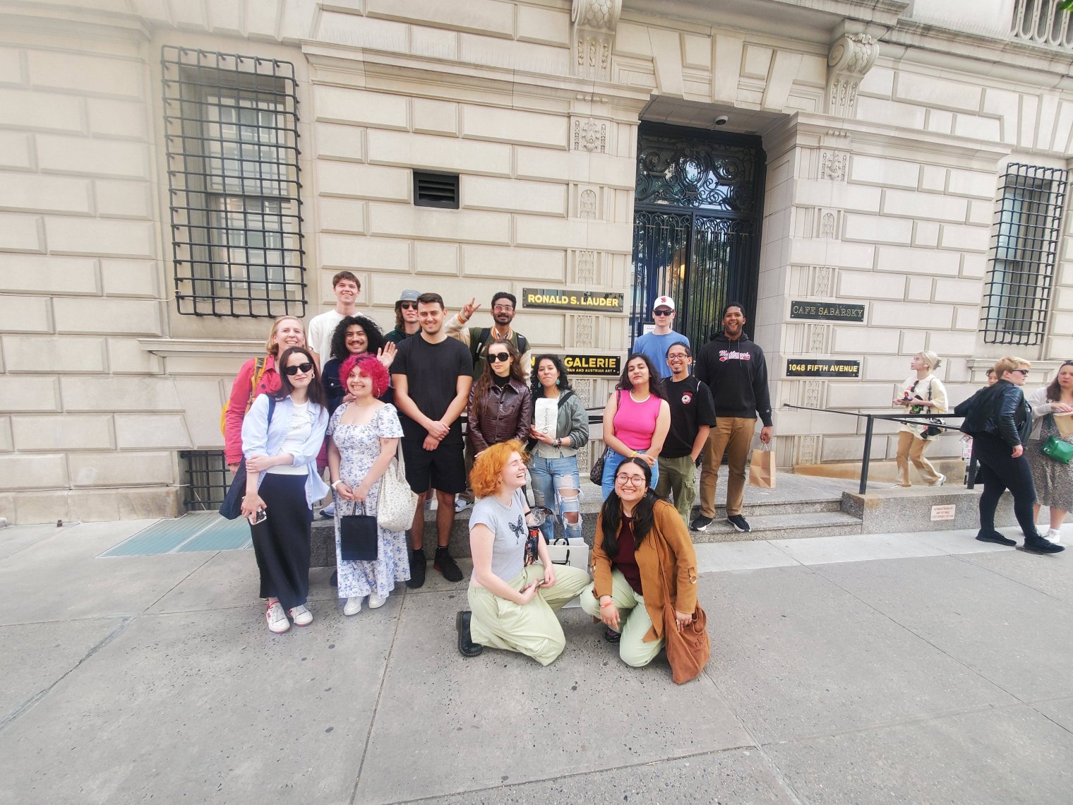 A group of college students pose in front of a Gilded-age brick building