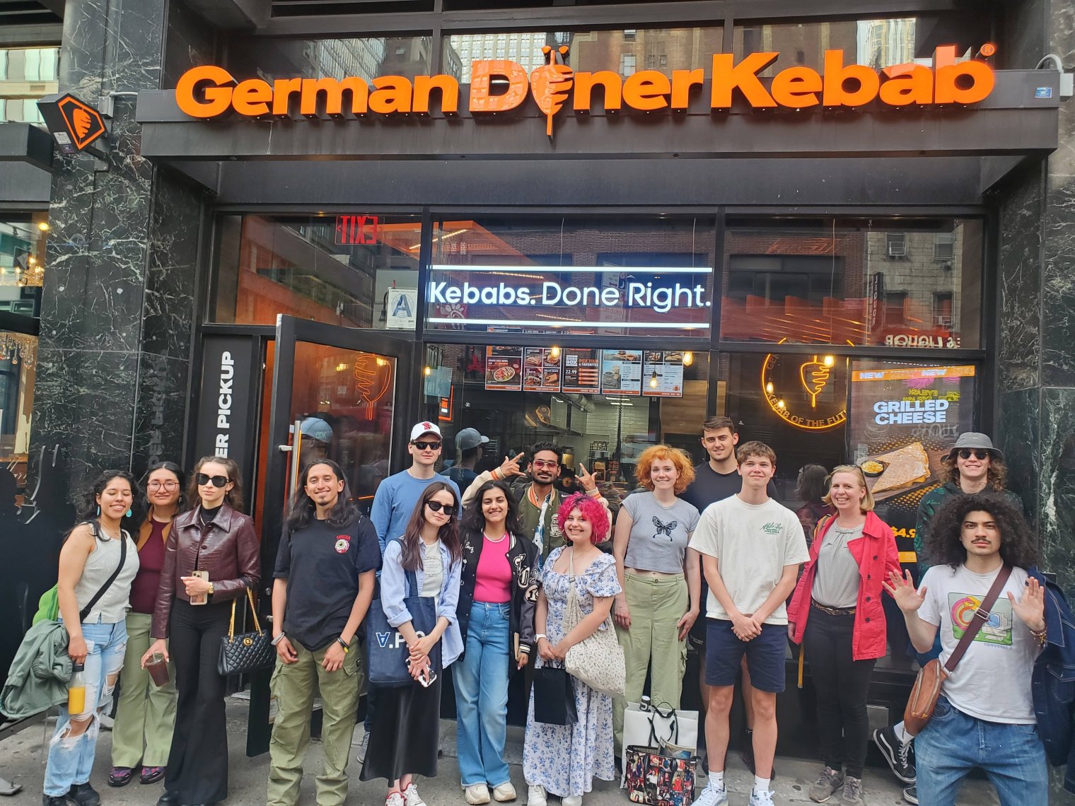 A group of college students pose in front of a "German Doner Kebab" restaurant