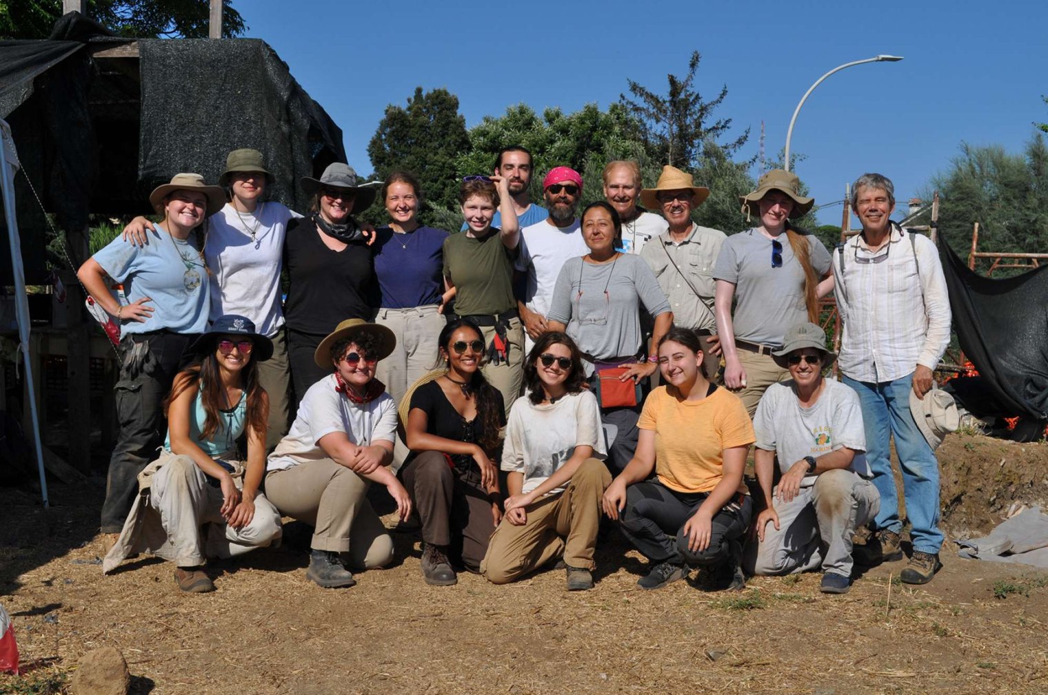 A group of college professors and students pose at an archaeological dig site