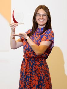 A woman wearing professional attire poses with a glass award