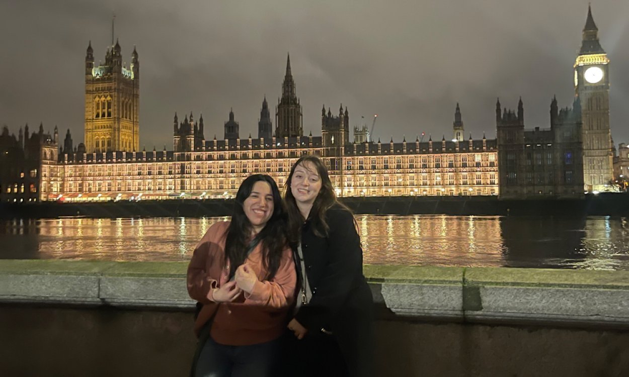 Two college students stand in front of British Parliament building and Big Ben at night