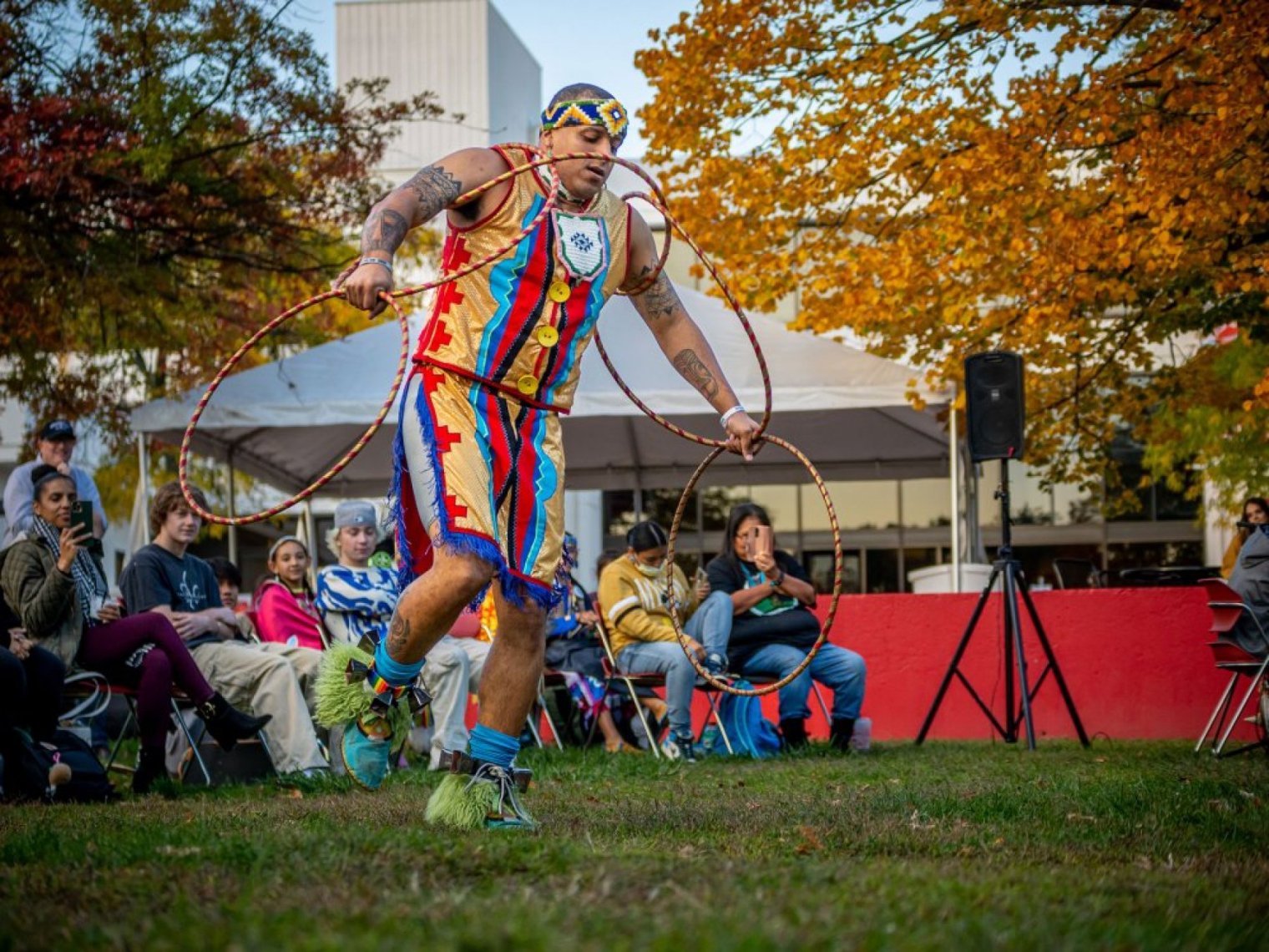 An Indigenous hoop dancer performs before an outdoor audience