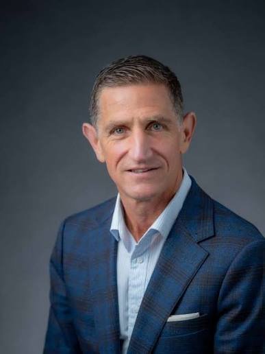 Headshot of CCOM Dean Keith Strudler with a dark gray background.