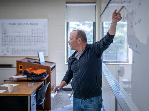 Male instructor pointing to white board