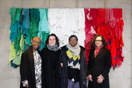 A group of four people pose in front of a sculpture of the Italian flag
