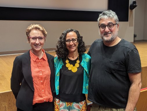 Three people pose for a photo in front of a stage