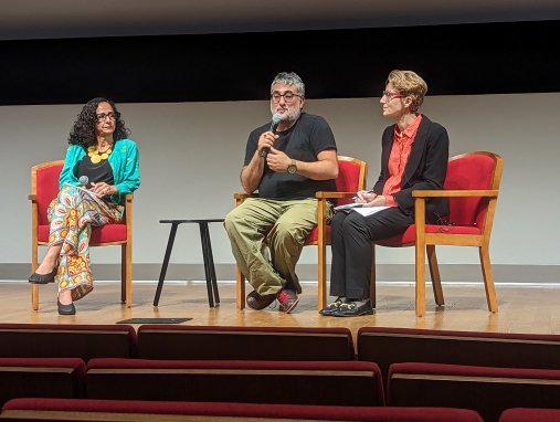 Three people sit on a stage and deliver a panel discussion