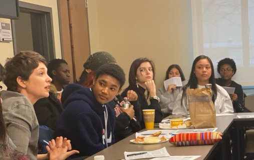 in a full room, on person is speaking during Philosophy for Lunch as others look on