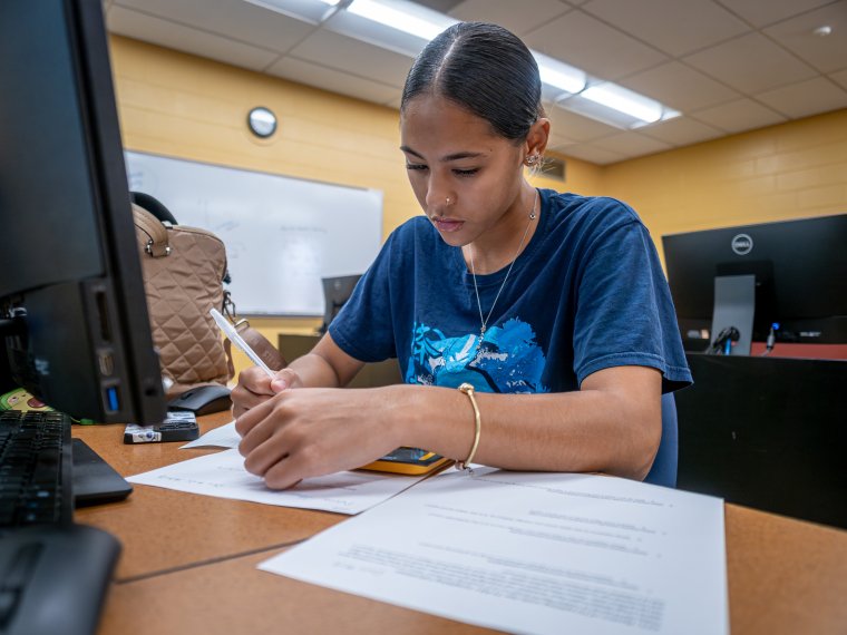 Woman writing in front of computer