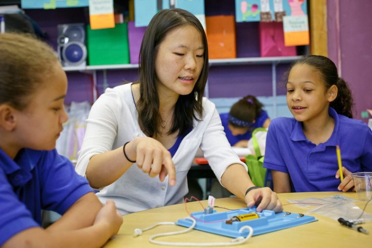 a teacher helps two students with work