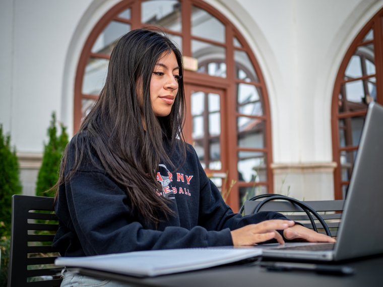 a student works on her laptop in the courtyard