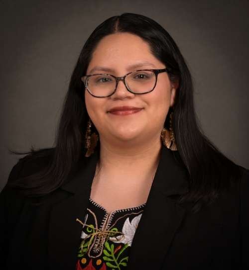 Headshot of Nereida Delgado Garcia in black blazer with Gray background