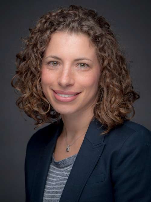 Headshot of Lauren Dinour Grey background and blue blazer